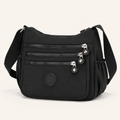 Willa London Everyday Organiser Crossbody Bag in Black, front three-quarter view showing three horizontal zips and silver-tone hardware