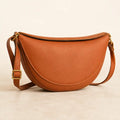 Willa London Crescent Crossbody Bag in Cognac on a warm ivory background