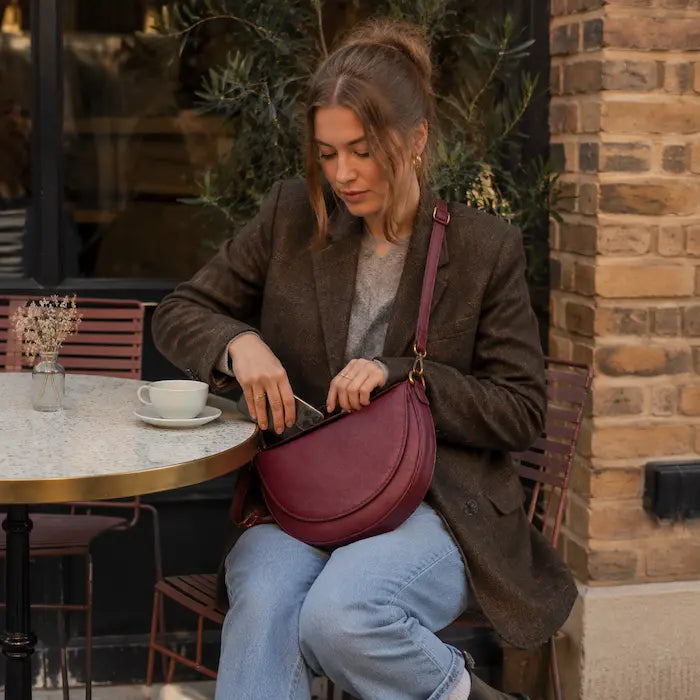 Burgundy crescent crossbody bag at a weekend cafe